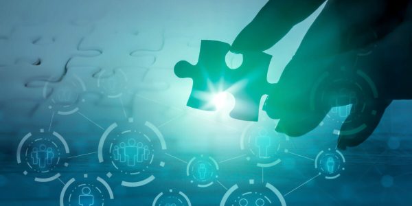 hand holding jigsaw piece with background of teamwork people connection